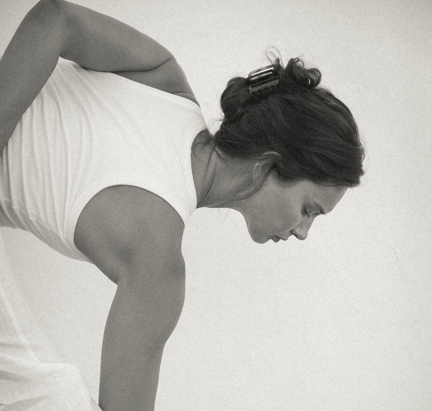 Renee Stewart, founder of The Movement Library leaning forward to hold her toe in a yoga posture, wearing a white matching top and trousers with her hair tied back